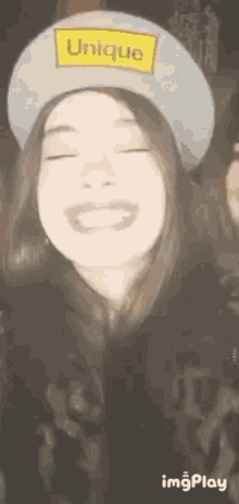 a woman wearing a hat that says `` unique '' is smiling .
