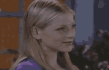 a close up of a woman 's face with a purple shirt on .