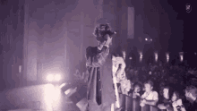 a man is singing into a microphone in front of a crowd that is watching him