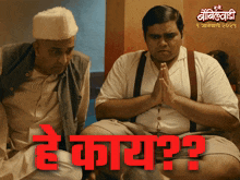 a man with a white hat sits next to another man with a question mark on his knee