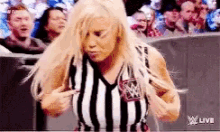 a woman is standing in front of a crowd wearing a striped shirt and pointing at her chest .