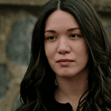 a woman with long dark hair looks at the camera