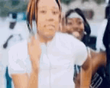 a woman in a white shirt is talking on a cell phone while standing next to a man .