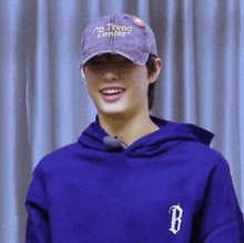 a young man wearing a purple hoodie and a hat that says i 'm trend center
