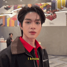 a young man wearing a red shirt and a black jacket says " i know "