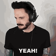 a man with a beard and mustache is wearing headphones and says yeah .