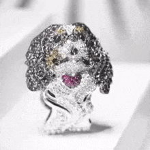 a close up of a ring in the shape of a dog with a heart in its mouth .