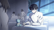 a man is sitting at a desk with a teddy bear behind him