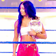 a woman in a wrestling ring holds a championship belt that says ' boss ' on it