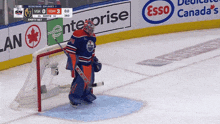 a hockey goalie stands in front of an empty net during a game sponsored by esso canada 's
