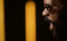 a close up of a man 's face with a beard wearing sunglasses and a ring in his ear .
