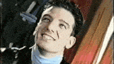 a man with curly hair is smiling and looking up at the camera .