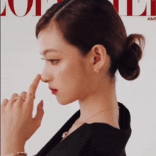 a woman with a bun on her hair is touching her nose in front of a vogue magazine cover