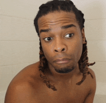 a shirtless man with dreadlocks and a beard makes a funny face
