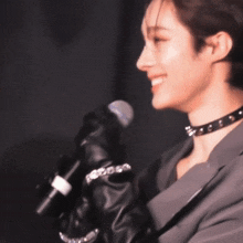 a woman wearing leather gloves and a choker smiles at the camera