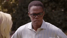 a man wearing glasses and a striped shirt is talking to a blonde woman .