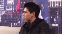a young man is sitting on a couch in front of a city skyline .