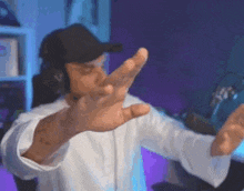 a man wearing headphones and a baseball cap is making a stop sign with his hands .