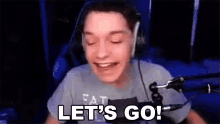 a man is sitting in front of a microphone and saying `` let 's go ! ''