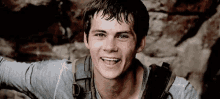 a young man with a backpack on his back is smiling and looking at the camera .