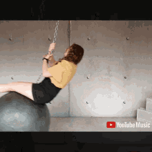a woman is sitting on a ball with a youtube music logo in the background