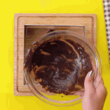 a person is pouring chocolate into a glass bowl .