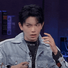 a young man wearing a denim jacket and a black shirt that says стиль