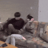 two people are sitting on a couch in a living room playing a video game .