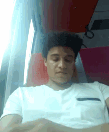 a man in a white shirt is sleeping on a train