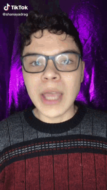 a man wearing glasses and a red and black sweater has a tiktok watermark on his face