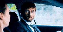 a man in a suit and tie is sitting in a car with a woman .