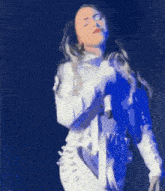 a woman in a white dress is singing into a microphone while dancing on a stage .
