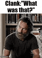 a man with a beard and a black shirt is sitting in a chair .
