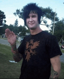 a man wearing a black shirt with an eagle on it waves his hand