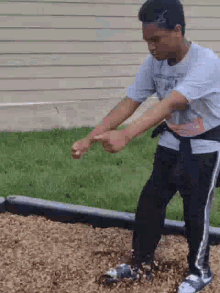 a young boy is standing on a pile of mulch in a playground .