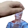 a hand is holding a statue of a man with a blue shirt on .