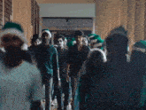 a group of people wearing santa hats are walking down a long hallway