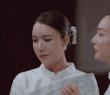 two women are standing next to each other and one has a pearl earring