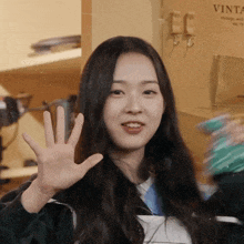 a woman is waving her hand in front of a sign that says vintage