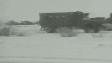a truck is driving through a snowy field .