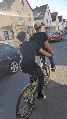 a man riding a bike with another man on the back of it