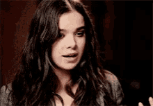 a woman with long dark hair is making a funny face while looking at the camera .