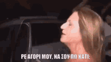 a woman is standing in front of a car with a foreign language written on her face .
