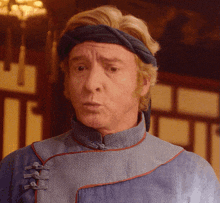 a man wearing a headband and a blue shirt looks surprised