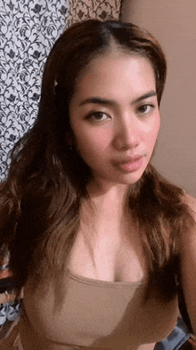 a woman in a tank top is taking a selfie in front of a wall .
