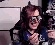 a woman wearing glasses and headphones is sitting in front of a microphone holding a toy .