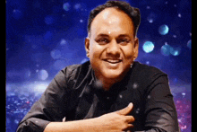 a man in a black shirt is smiling and giving a thumbs up sign