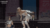 a female wrestler is kneeling down in front of a stardom sign