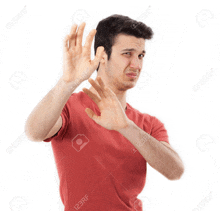 a young man in a red shirt is making a stop sign with his hands .