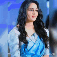 a woman wearing a blue saree and a pearl necklace